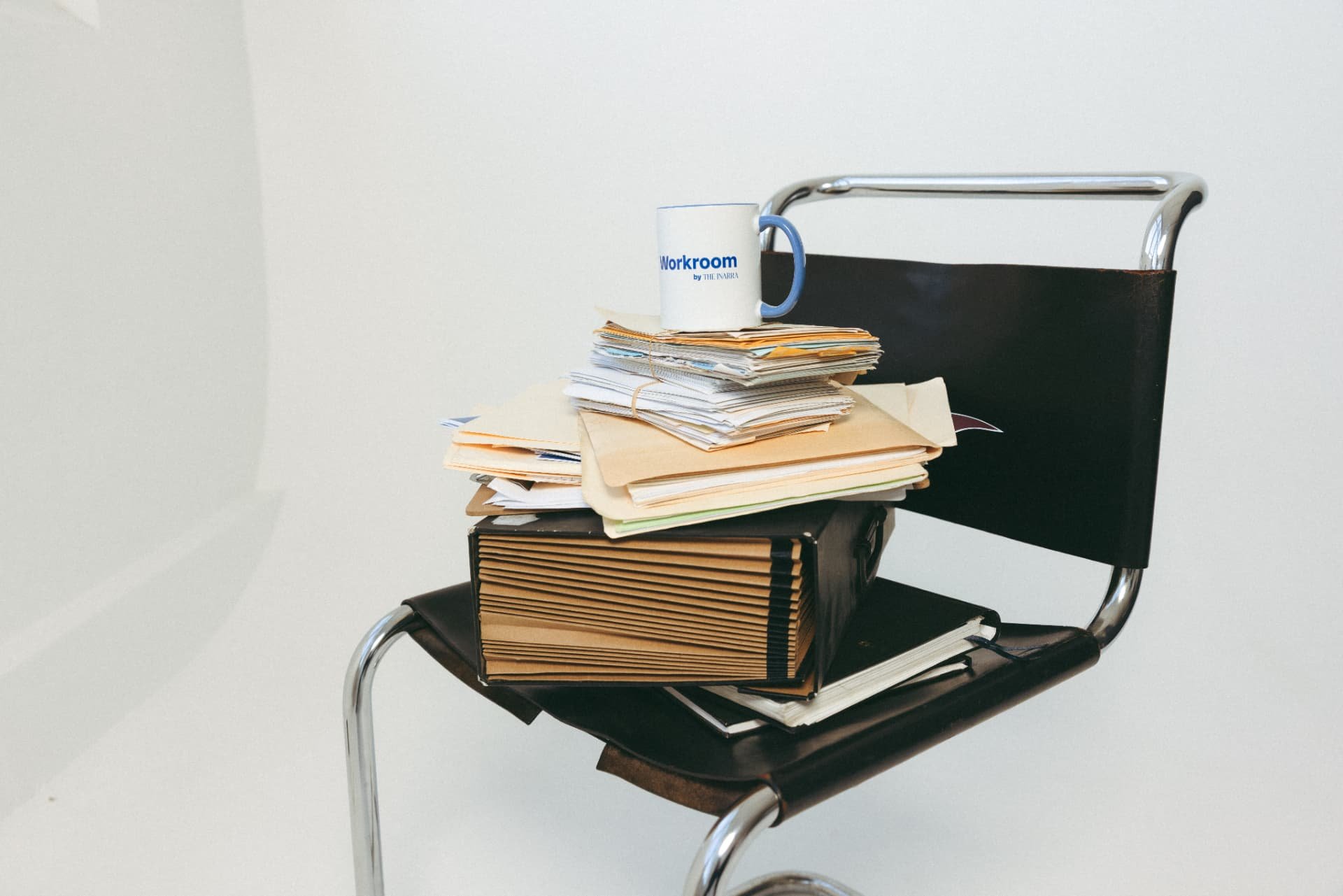 A Workroom mug on a stack of papers and folders on a chair